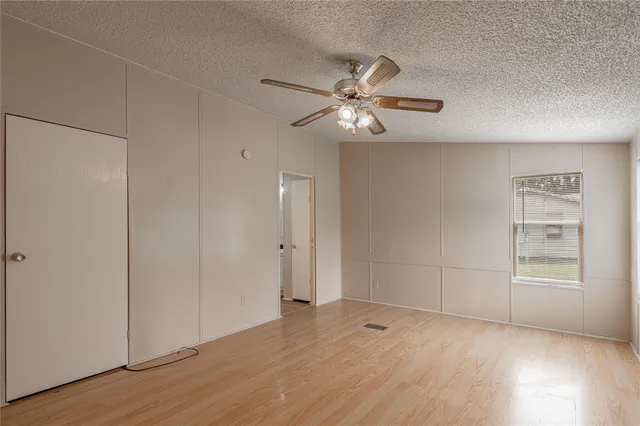 an empty room with wooden floor closet and windows