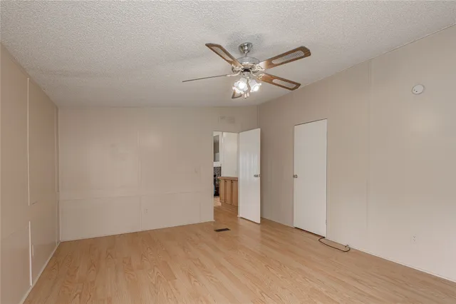 an empty room with wooden floor and ceiling fan