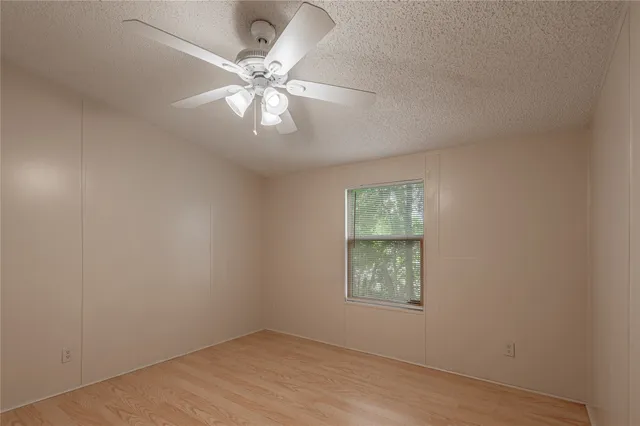 an empty room with a window and a fan