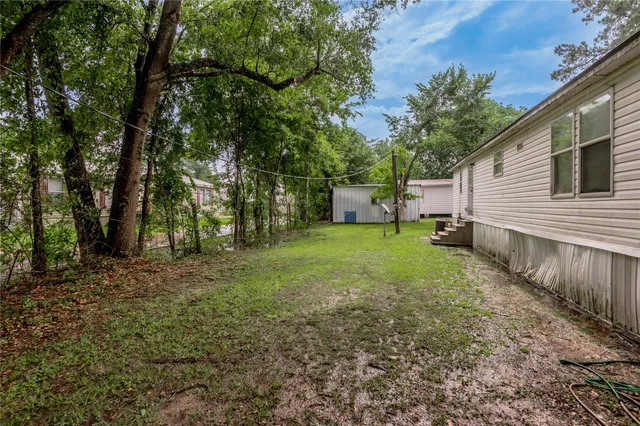 a view of a backyard with large trees and wooden fence