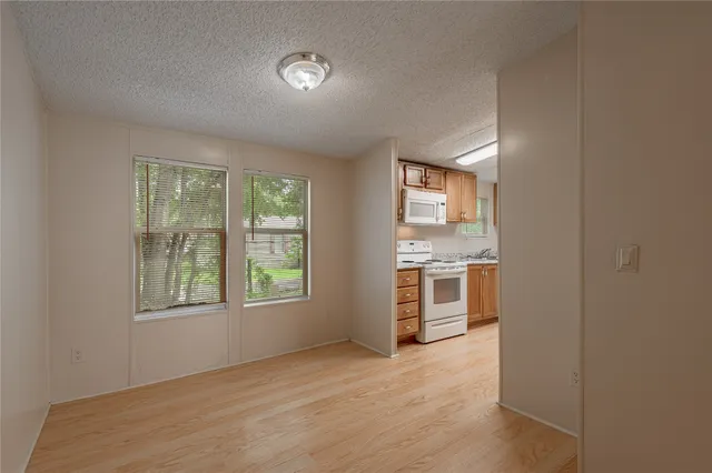 a view of an empty room with a window and kitchen
