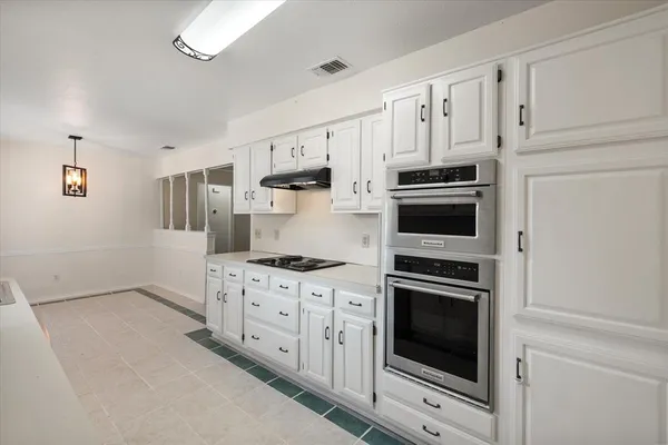 a kitchen with white cabinets and appliances