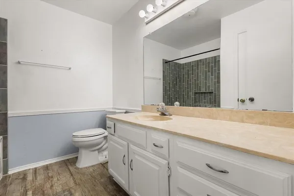 a bathroom with a granite countertop sink mirror vanity and toilet