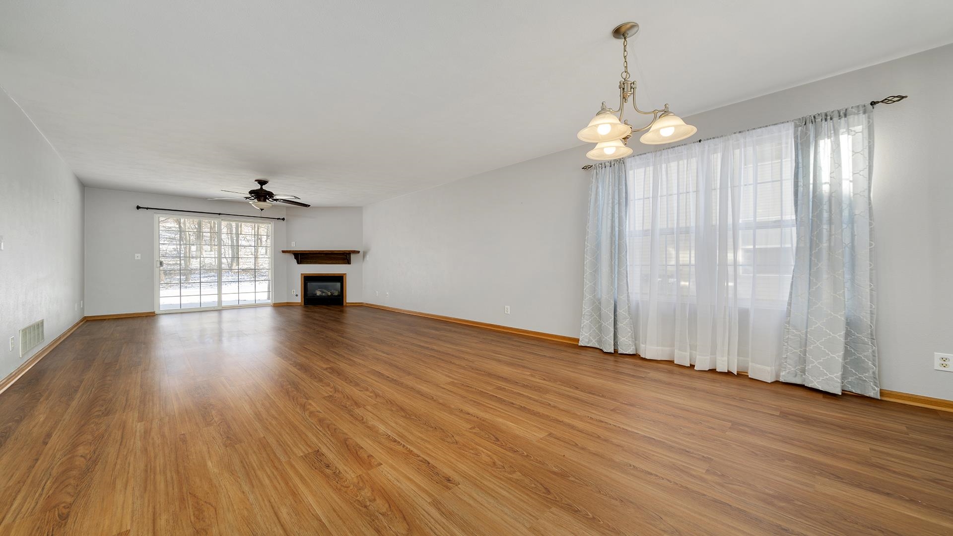 443 Mill Ridge Drive Byron, IL 61010 - Photo 2 of 25 an empty room with wooden floor chandelier and windows