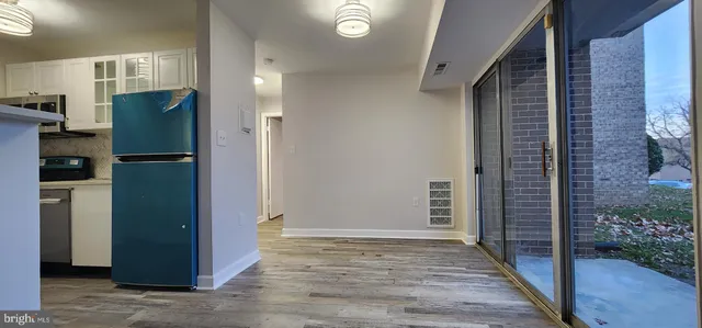 a view of a kitchen with refrigerator and wooden floor
