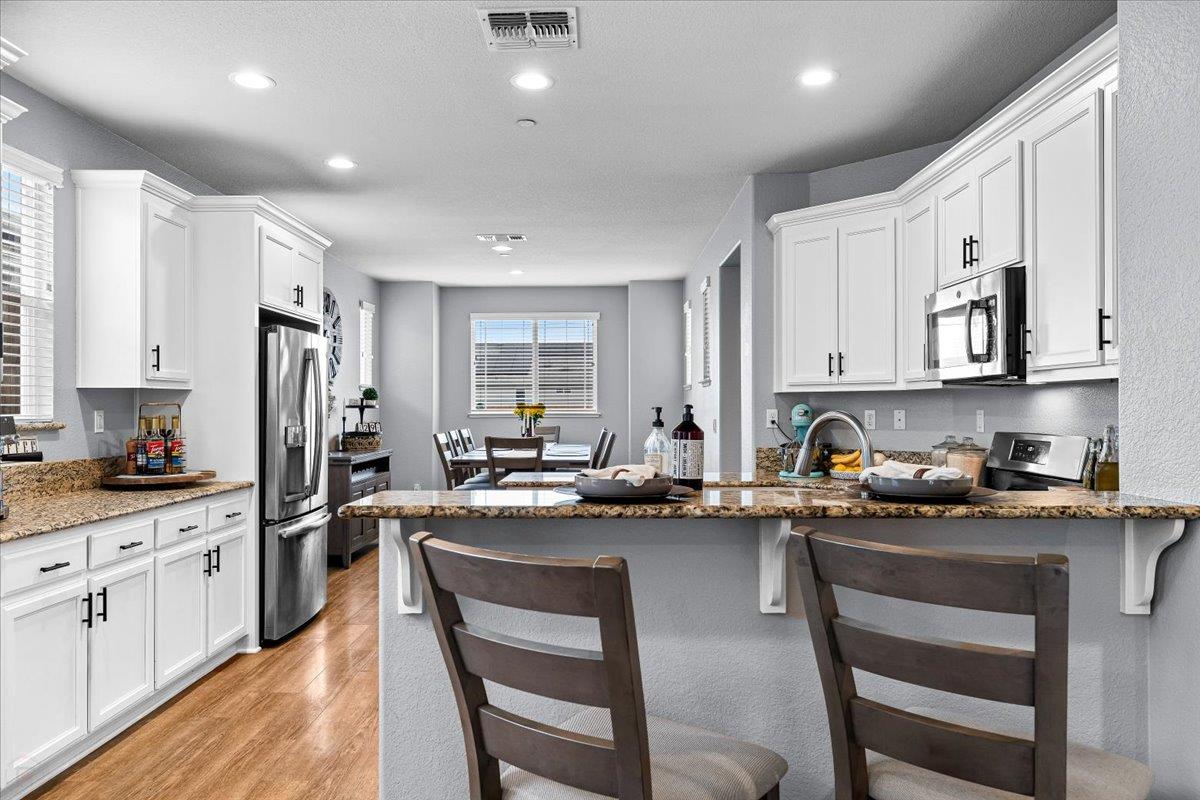 6617 Cervi Road Riverbank, CA 95367 - Photo 13 of 51 a kitchen with stainless steel appliances granite countertop a stove top oven a sink dishwasher a dining table and chairs with wooden floor