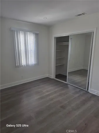 an empty room with wooden floor closet and windows