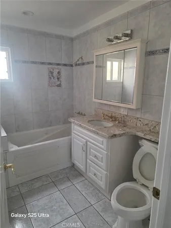 a bathroom with a granite countertop toilet sink and mirror