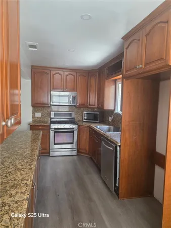 a kitchen with kitchen island wooden floors appliances and cabinets