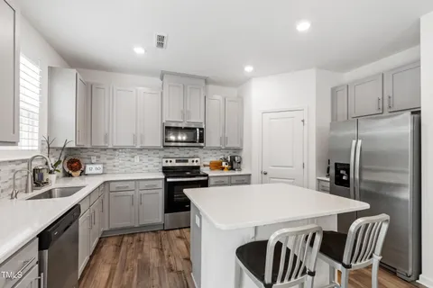 a kitchen with a sink a stove a refrigerator a center island and a window