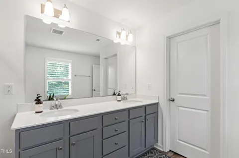 a bathroom with double vanity sink a mirror and a window