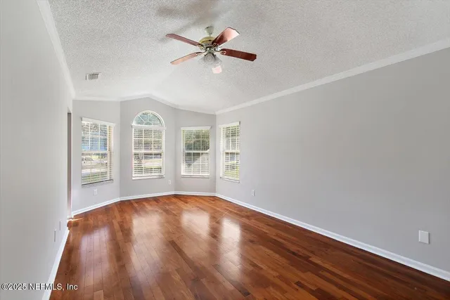 a view of empty room with wooden floor and fan