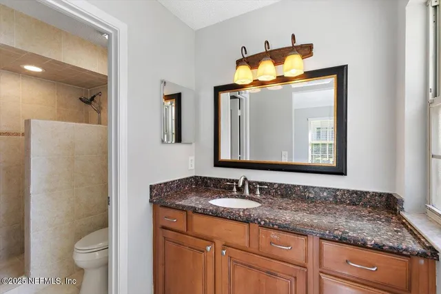 a bathroom with a granite countertop sink toilet and mirror
