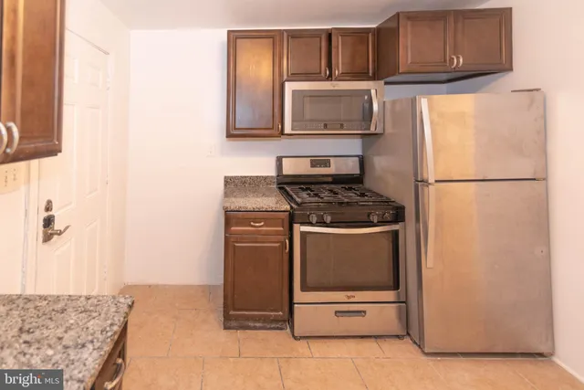 a kitchen with granite countertop a refrigerator and a stove top oven