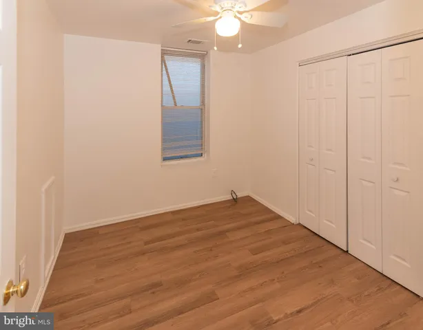 an empty room with wooden floor and fan