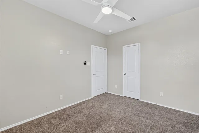 an empty room with a ceiling fan and carpet