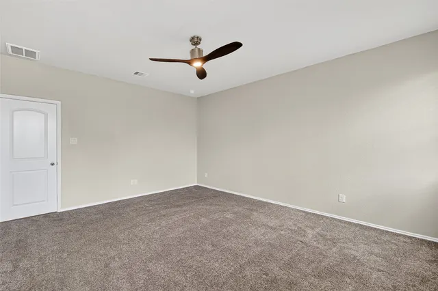 an empty room with a ceiling fan and window