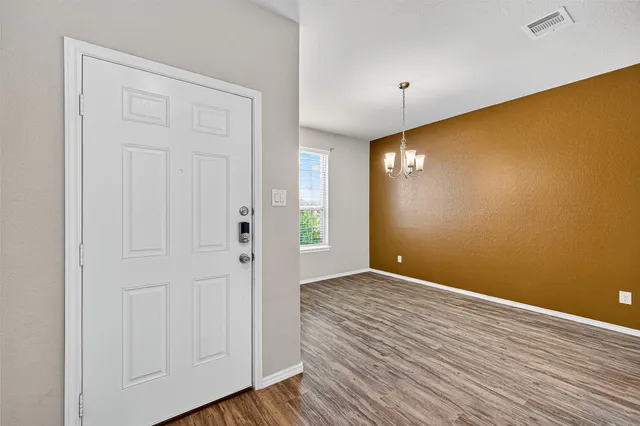 a view of an empty room with wooden floor and closet