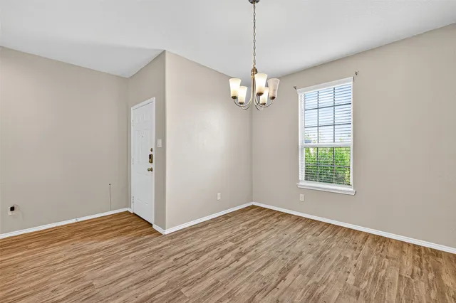 a view of empty room with wooden floor window and chandelier