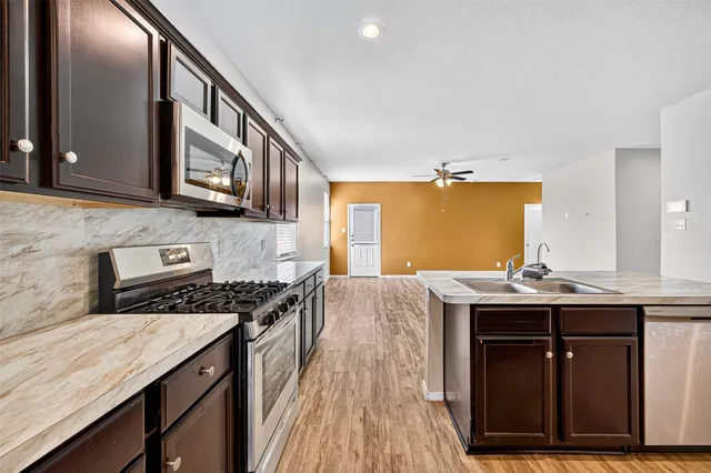 a kitchen with stainless steel appliances granite countertop a sink stove and cabinets