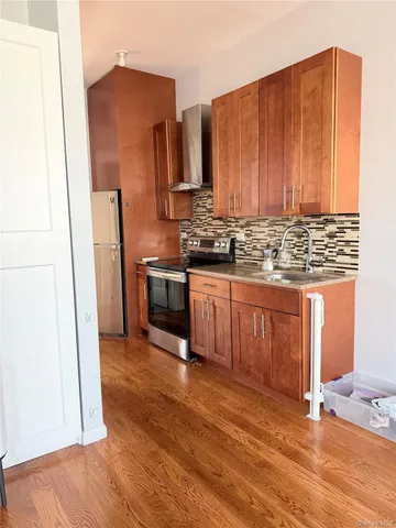 a kitchen with stainless steel appliances granite countertop a refrigerator a sink and wooden floors