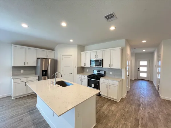 a kitchen with stainless steel appliances kitchen island sink refrigerator and cabinets
