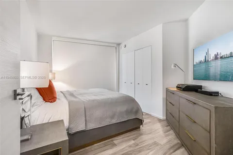 a bedroom with a bed and a flat tv screen on a dresser