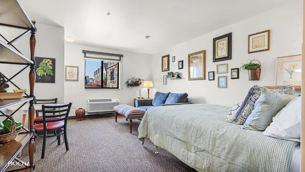 a bedroom with a bed a desk and chair with wooden floor
