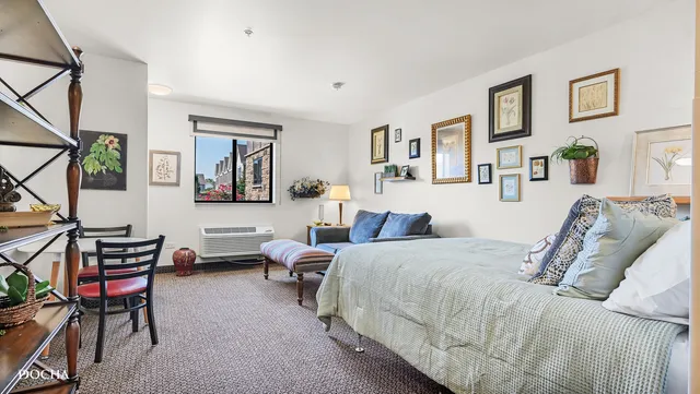 a bedroom with a bed a desk and chair with wooden floor