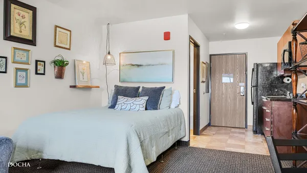 a bedroom with a bed painting on wall and a desk