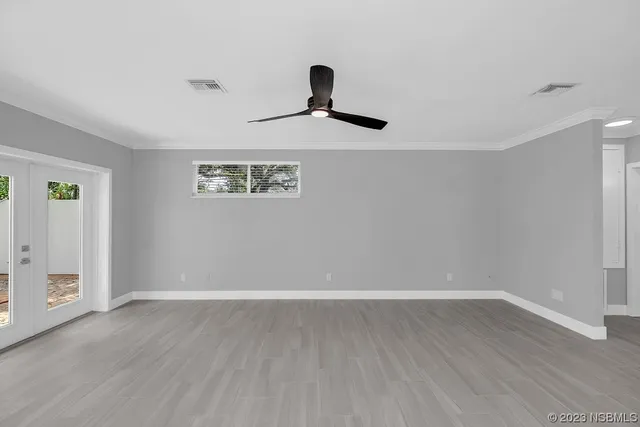 a view of an empty room with a window and wooden floor
