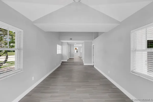 an empty room with wooden floor chandelier and windows