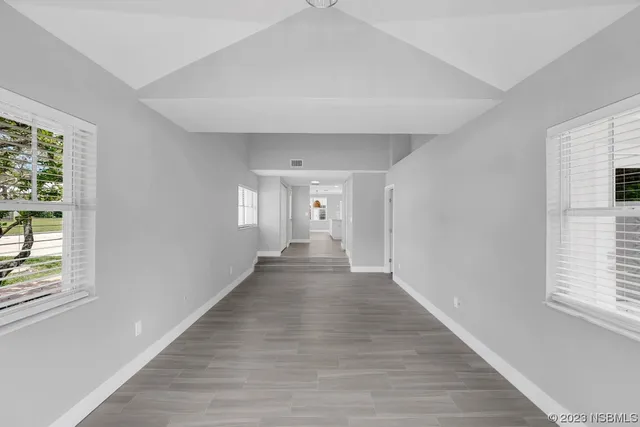 an empty room with wooden floor chandelier and windows