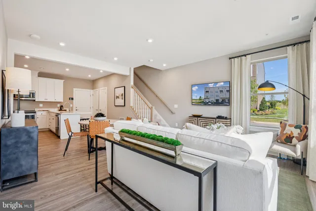 a living room with stainless steel appliances furniture a rug and a kitchen view