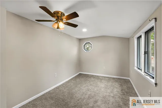 an empty room with windows and ceiling fan