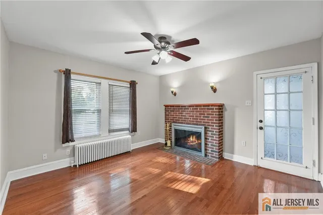 a view of an empty room with wooden floor fireplace and a window