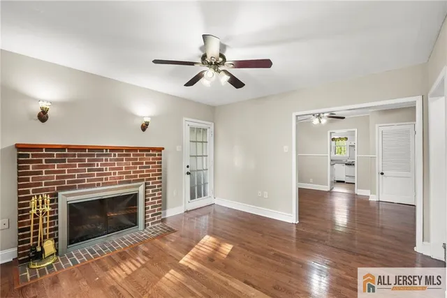 a view of an empty room with kitchen and fireplace