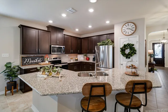 a kitchen with granite countertop a table chairs stove top oven and microwave