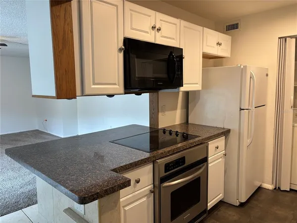 a kitchen with granite countertop a sink stove and refrigerator