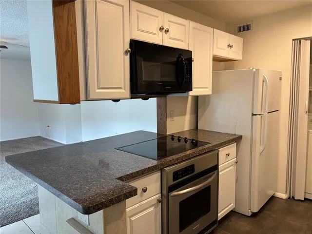 a kitchen with granite countertop a sink stove and refrigerator