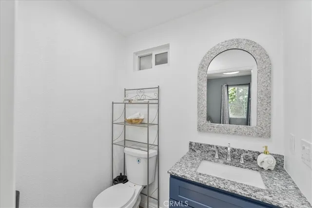 a bathroom with a granite countertop sink mirror vanity and toilet