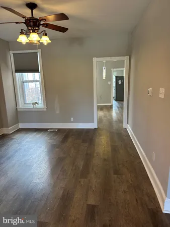 an empty room with wooden floor chandelier fan and windows