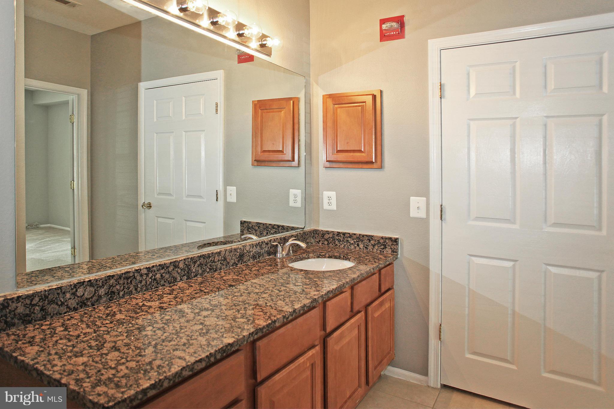 1530 Spring Gate Dr., Unit 9103 McLean, VA 22102 - Photo 14 of 30 a bathroom with a granite countertop sink and a mirror