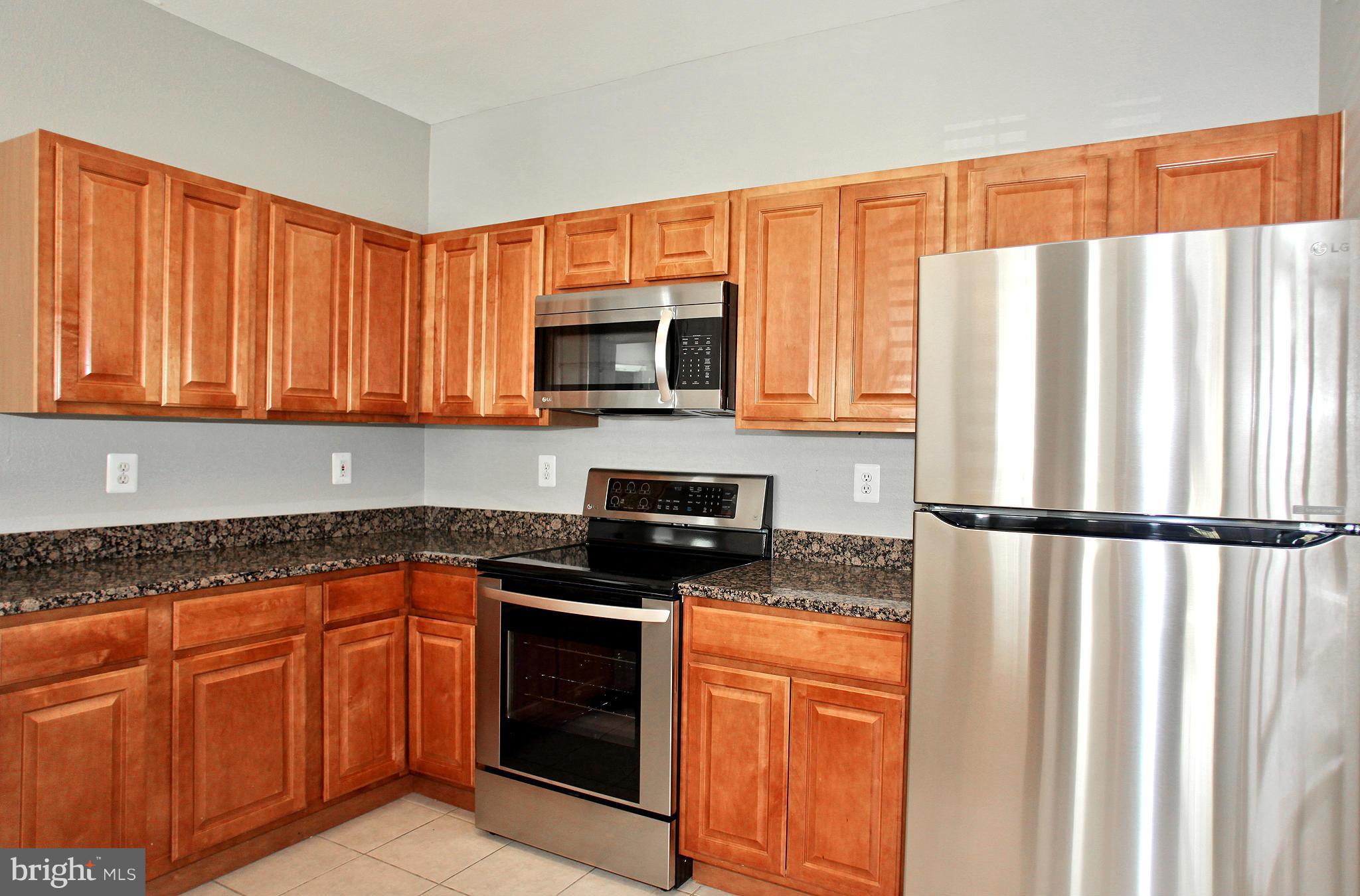 1530 Spring Gate Dr., Unit 9103 McLean, VA 22102 - Photo 4 of 30 a kitchen with granite countertop white cabinets stainless steel appliances a sink and a window