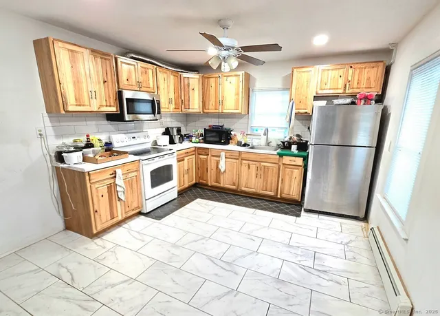 a kitchen with stainless steel appliances granite countertop a stove a sink a refrigerator a window a dining table and chairs