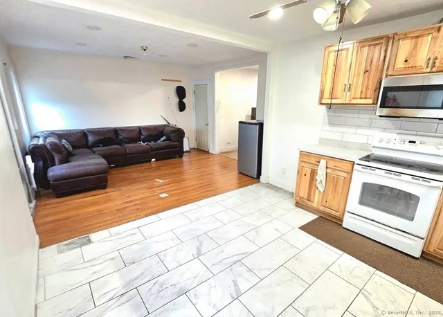 a living room with stainless steel appliances furniture a rug and a window