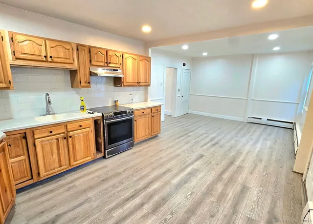 a kitchen with stainless steel appliances granite countertop a sink a stove a refrigerator cabinets and wooden floor