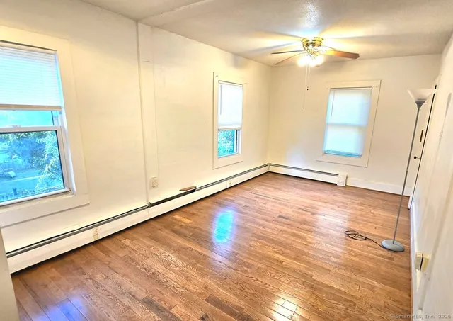 a view of an empty room with wooden floor and a window