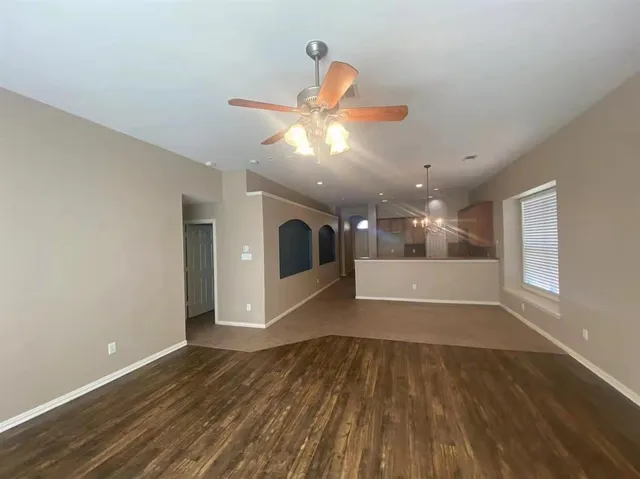 a view of an empty room with window and wooden floor