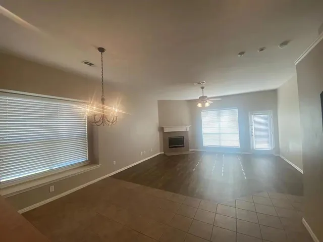 a view of an empty room with window and chandelier fan